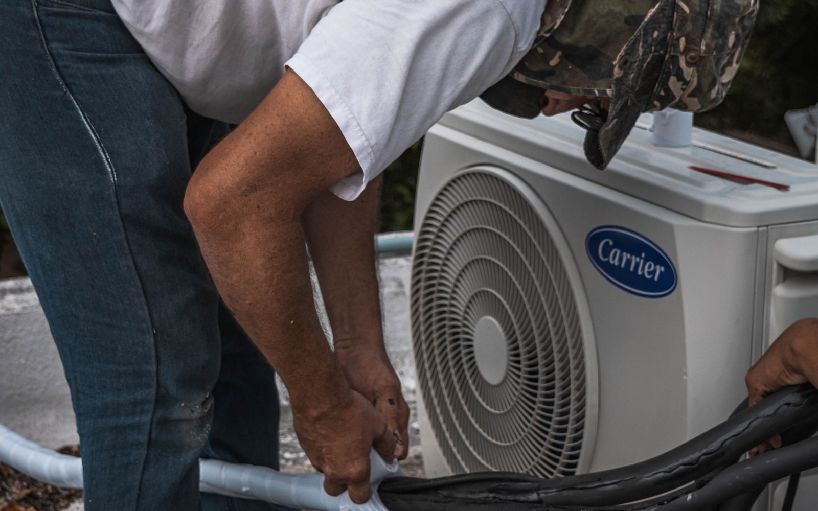 Technician securing a service hose connection on HVAC equipment