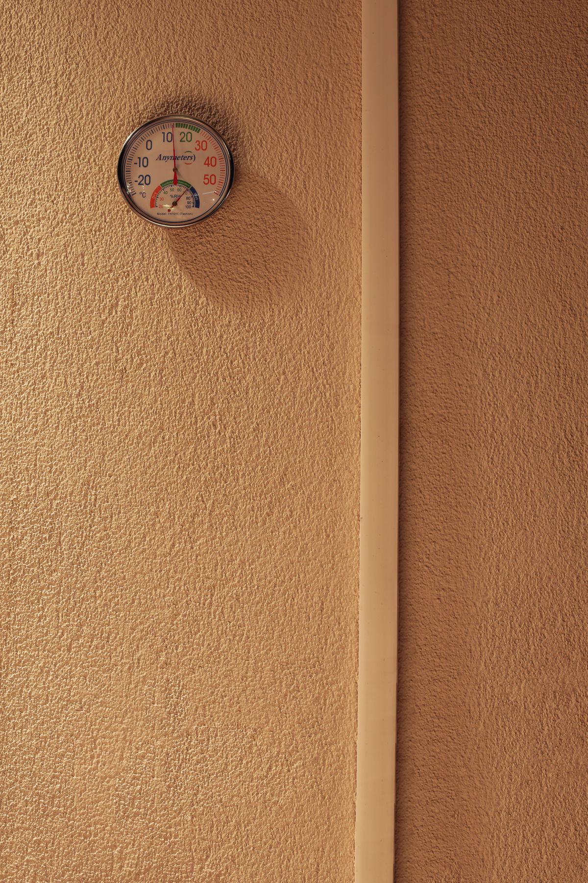 Round indoor hygrometer mounted on a textured wall
